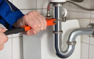 Man working on a pipe under a sink