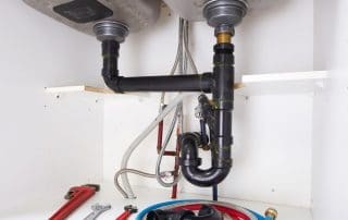 Plumbing repair tools underneath a kitchen sink