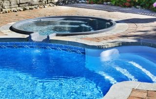 Outdoor inground residential swimming pool in backyard with hot tub