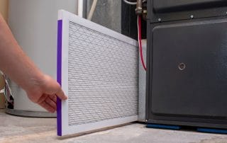 Person changing an air filter in a high efficiency furnace