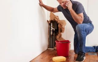 Middle aged man with a burst water pipe phoning for help