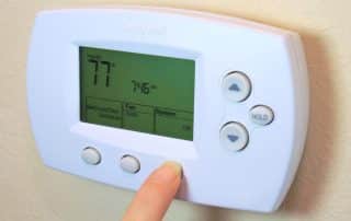 Person adjusting settings on a thermostat