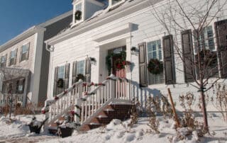 exterior of homes decorated for holidays with snow on the ground